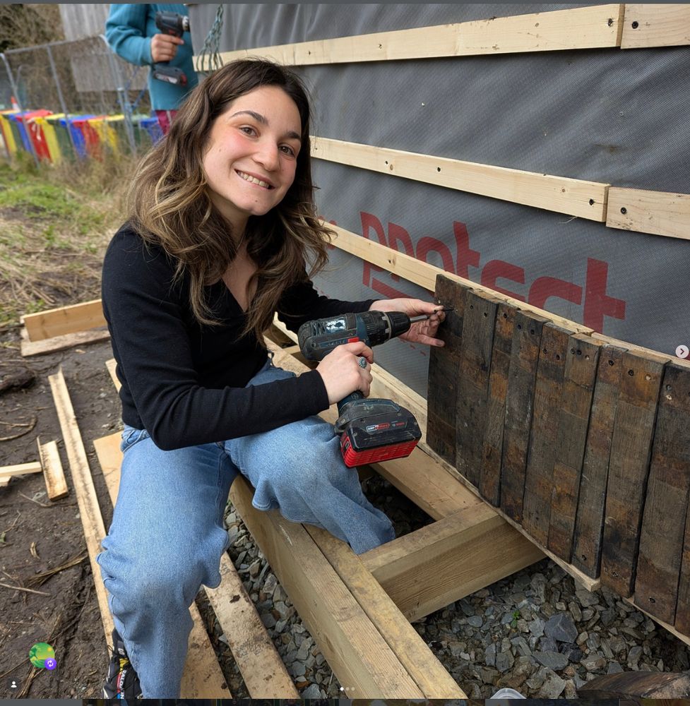 Student attaching reclaimed whiskey barrel staves to a structure at Greenacre
