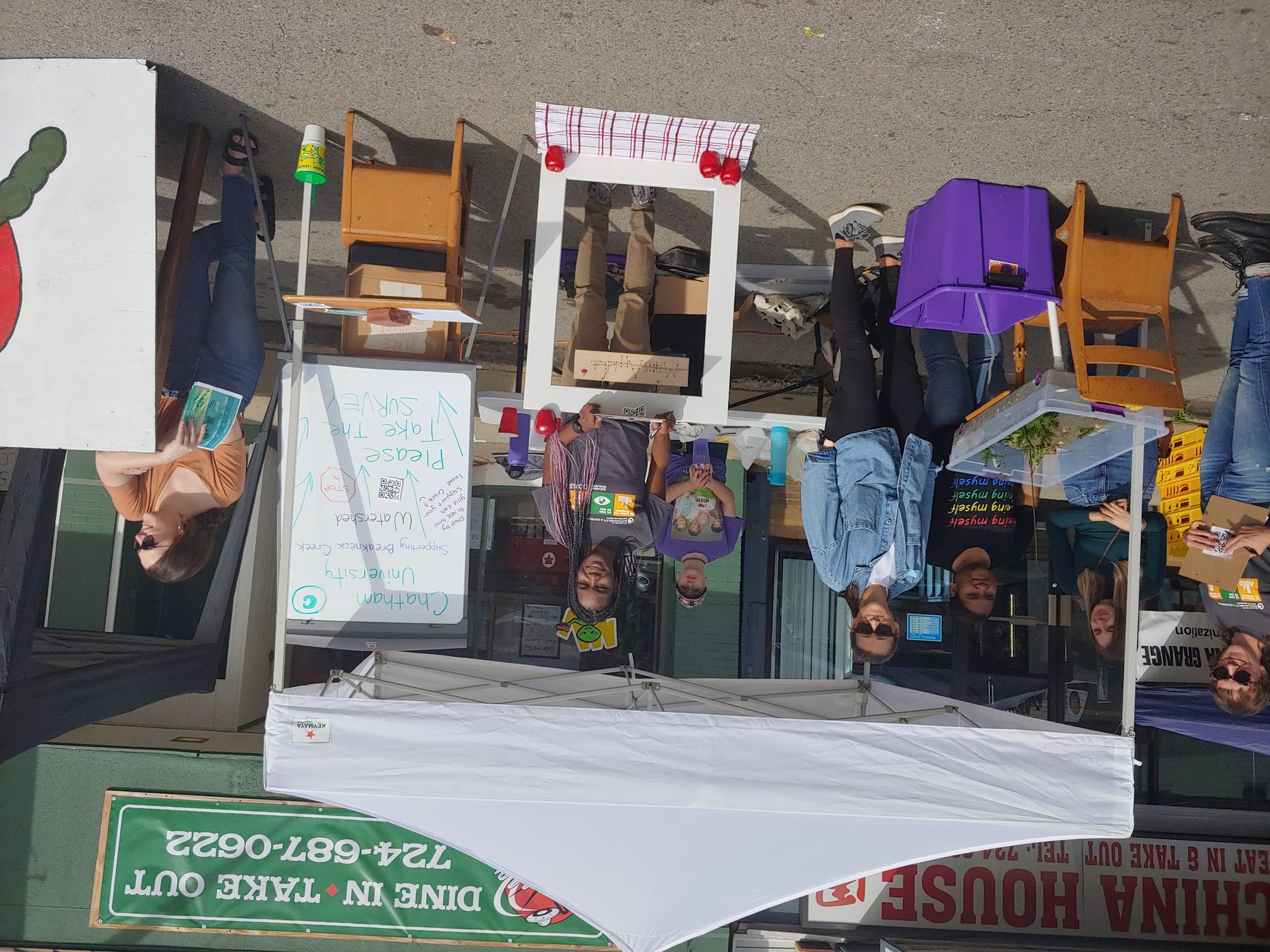 Chatham students running a street stall at a town festival, with a
               watershed survey board and a tank of creek water